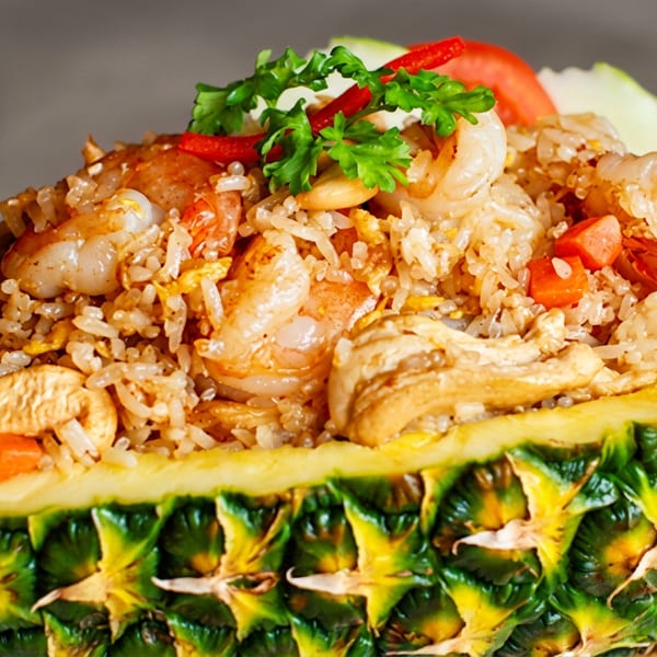 Pineapple fried rice with shrimp, cashews, and vegetables served in a hollowed-out pineapple.